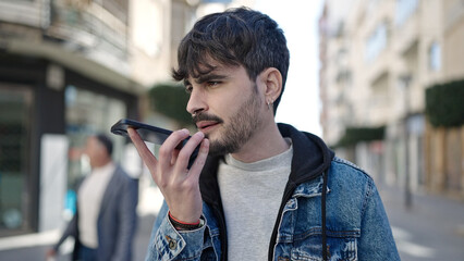 Young hispanic man sending voice message with smartphone at street