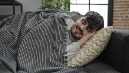 Young hispanic man lying on sofa sleeping at home