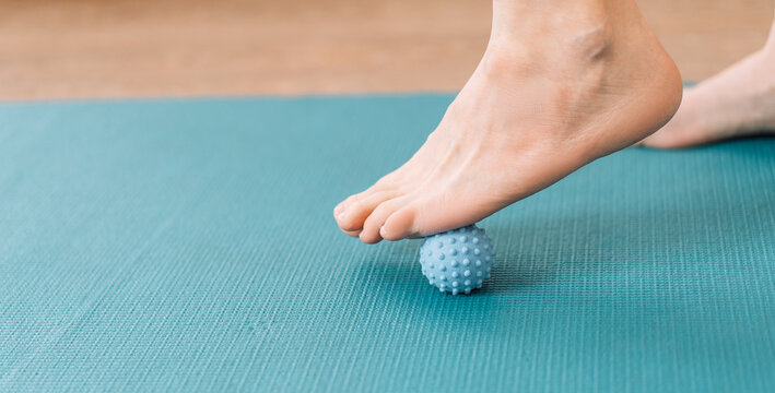 Lady kneading her feet with massage ball.