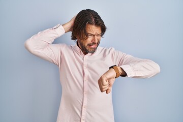 Handsome middle age man wearing elegant shirt background looking at the watch time worried, afraid...