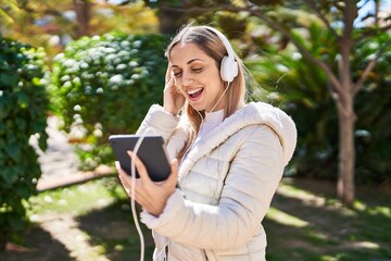 Young woman smiling confident listening to music at park