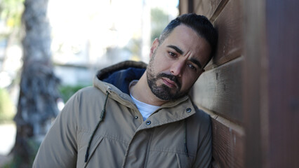 Young hispanic man standing with sad expression at street