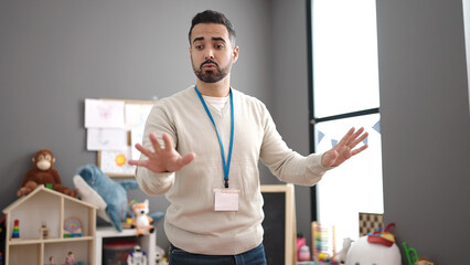 Young hispanic man preschool teacher asking for silence at kindergarten