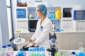 Fototapeta premium Brunette woman working at scientist laboratory looking to side, relax profile pose with natural face and confident smile.
