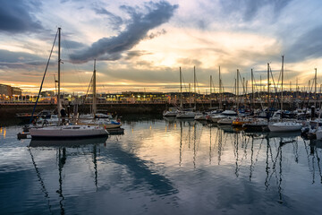 Stunning sunset in the marina of Gijon with reflections in the sea water, Asturias, Spain.