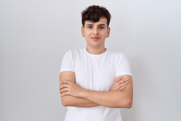 Young non binary man wearing casual white t shirt happy face smiling with crossed arms looking at...