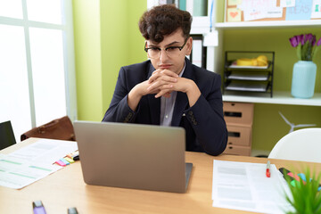 Non binary man business worker using laptop with relaxed expression at office