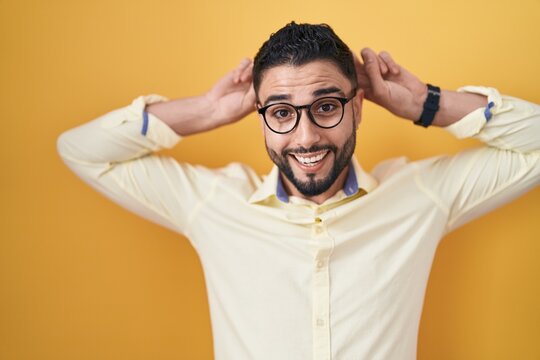 Hispanic young man wearing business clothes and glasses posing funny and crazy with fingers on head as bunny ears, smiling cheerful