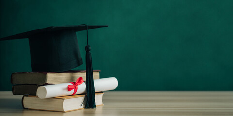 A mortarboard and graduation scroll, tied with red ribbon, on a stack of old battered books.Concept...