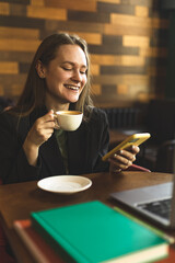 A girl works at a laptop in a cafe. Freelanser girl. Happy and successful girl works remotely.