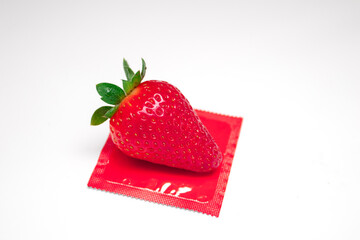 Strawberry with red condom on white background. Sex concept