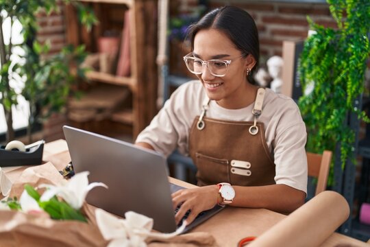 Young beautiful hispanic woman florist smiling confident using laptop at florist