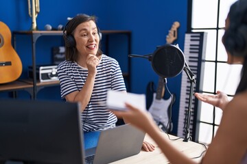 Two women musicians listening to music composing song at music studio