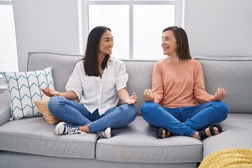 Two women mother and daughter doing yoga exercise at home