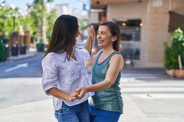 Two women mother and daughter smiling confident dancing at street