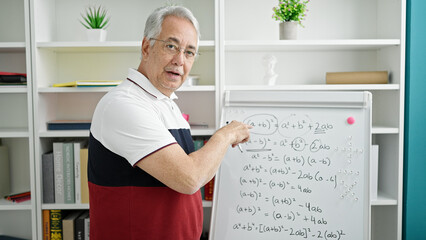 Middle age man with grey hair teacher teaching maths lesson at university classroom