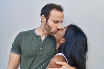 Man and woman interracial couple hugging each other and kissing over white background