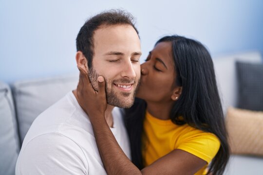 Man and woman interracial couple hugging each other and kissing at home