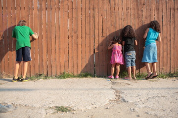 Children peeking through a fence