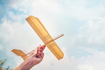 Boy flying a toy Balsa wood airplane into the sun and sky