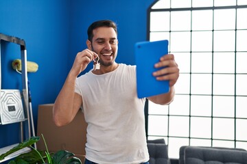Young hispanic man holding key make selfie by touchpad at new home