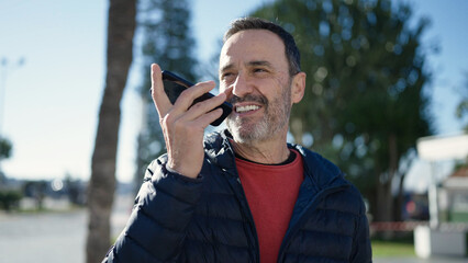 Middle age man sending voice message with smartphone at park