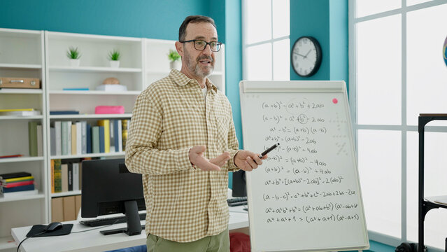 Middle age man teacher teaching maths lesson at classroom