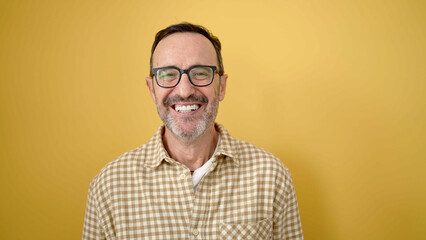 Obraz premium Middle age man smiling confident wearing glasses over isolated yellow background