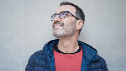 Middle age man smiling confident looking to the sky at street