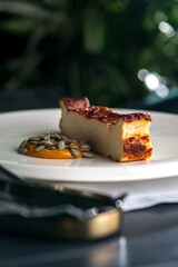 Piece of cheesecake on a plate.Basque cheesecake with sea buckthorn caramel.