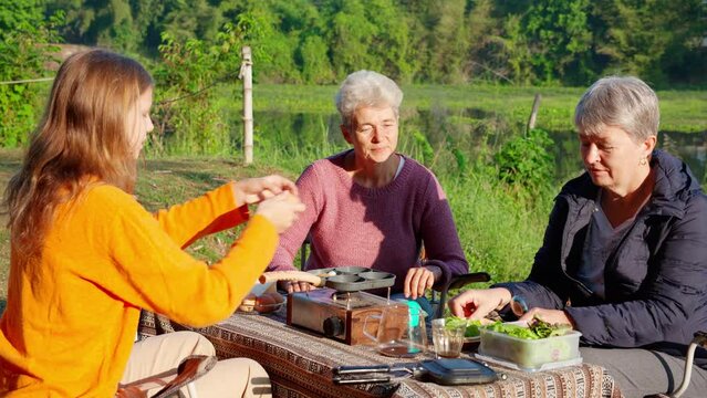 Two senior woman and teenager talking and leisure in camping, activity recreation and leisure picnic while breakfast together in morning in weekend, travel trip in holiday, party in vacations.