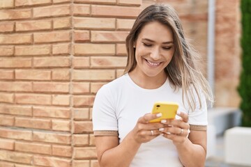 Young caucasian woman smiling confident using smartphone at street