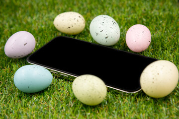 Phone with blank empty screen on background of easter eggs with  in  on green grass. Space for text. Happy Easter! Smartphone mockup,