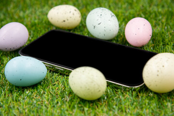 Phone with blank empty screen on background of easter eggs with  in  on green grass. Space for text. Happy Easter! Smartphone mockup,