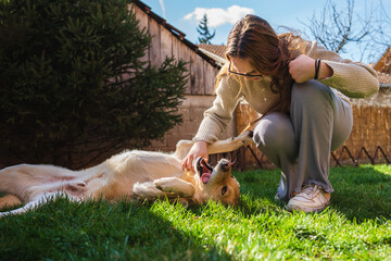 A young girl student is petting and feeding and playing with her pet dog labrador in backyard	
