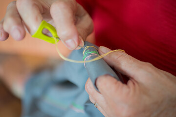 Obraz na płótnie Canvas Close up of senior woman hands doing embroidery on a cloth