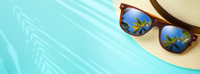 Fototapeta na wymiar concept vacation and summer travel banner. Happy holidays on sandy tropical sea beach. Panama hat and sunglasses with a reflection of the sandy trovic beach and palm trees;