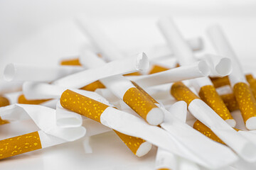Lots of broken cigarettes on a pile close up. Harm of smoking