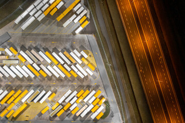 View from a height in the evening of a large parking lot with trucks and trailers by the road