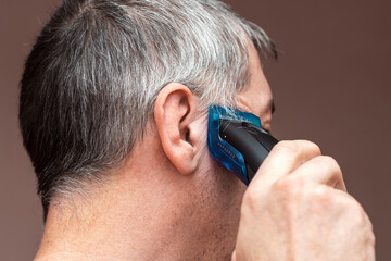 Man cutting his own hair with a clipper