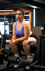 Fototapeta na wymiar Fit Indian Girl on Leg Curls Machine in the Gym looking confident and beautiful.