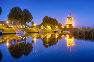 Fototapeta na wymiar Dokkum, Netherlands. The famous windmill. Journey through the Netherlands. Historical sites and famous places. Dutch canals with boats.