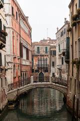 Fototapeta na wymiar Venice, view of a canal on a misty day, bridge over canal in the background.