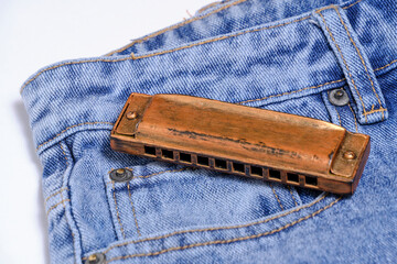 Harmonica, musical instrument, lies on denim pants.