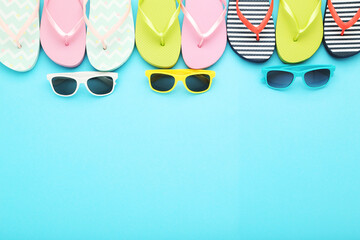 Obraz na płótnie Canvas Colorful flip-flops with sunglasses on blue background