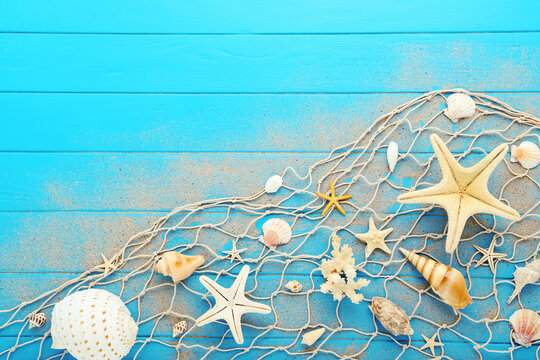 Starfishes with seashells and fishing net on blue wooden table