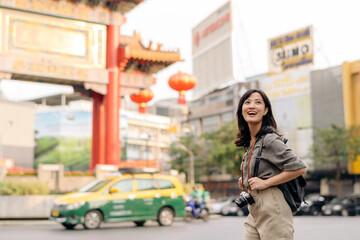 Fototapeta premium Young Asian woman backpack traveler enjoying China town street food market in Bangkok, Thailand. Traveler checking out side streets.