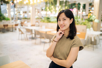 Smiling beautiful asian woman standing in cafeteria at shopping mall.