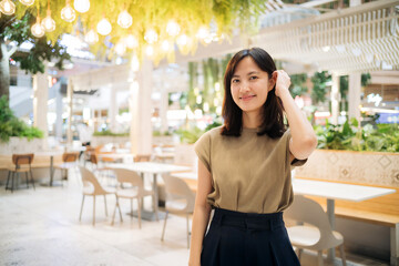 Smiling beautiful asian woman standing in cafeteria at shopping mall.