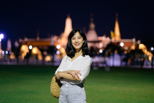 Portrait young beautiful asian woman smiling while travel at Temple of the Emerald Buddha or Wat Phra Kaew in night view point, Bangkok, Thailand.